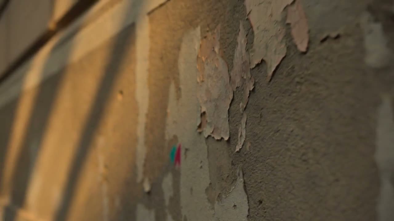 Cinematic fly-through over weathered sunlit walls and facades — where a brand mark leaves the file and lands in the world